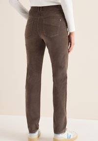 Bruine corduroy broek met een rechte snit, twee achterzakken en een gladde textuur. Draag met witte en blauwe sneakers.