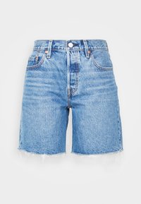 Blå denimshorts med hög midja, fransad fåll, två framfickor och knappstängning. Tyget har en ljus tvätt med subtil blekning.