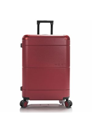 Red hardshell suitcase with a textured surface, four wheels, a retractable handle, and embossed brand name on the side.