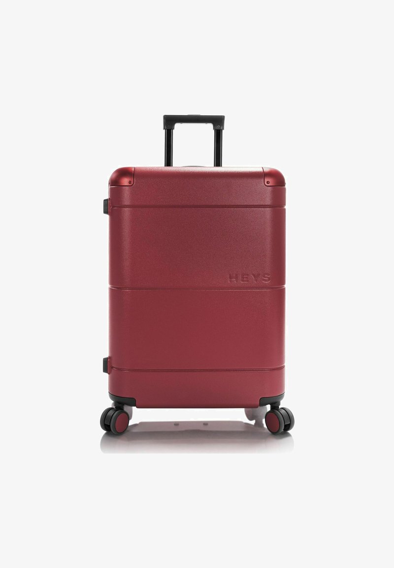 Roter Hartschalenkoffer mit strukturiertem Oberflächenmaterial, vier Rädern, einem ausziehbaren Griff und eingeprägtem Markennamen an der Seite.