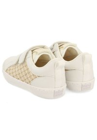 Zapatillas blancas con un panel lateral de malla crema texturizada, correa ajustable y suela de goma. Presenta un logotipo en el talón.