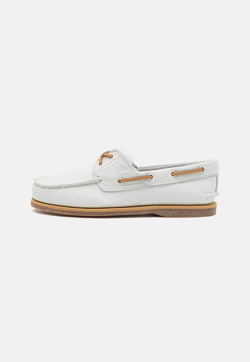 White leather boat shoe with embossed logo, brown accents, and a moccasin-style stitched toe. Flat brown rubber sole for grip.