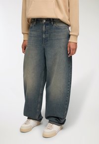 Jeans in denim oversize di colore azzurro chiaro con vita alta, caratterizzati da un design sbiadito e dal classico styling a cinque tasche. Abbina a sneakers di colore off-white.