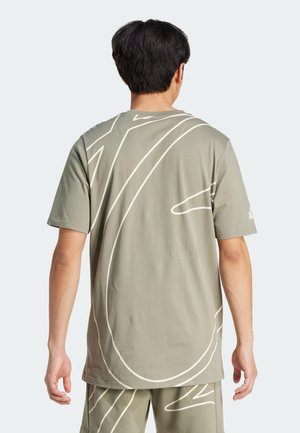 Homme de dos portant un t-shirt vert olive clair et un short assorti avec des motifs de lignes abstraites blanches sur un fond uni.