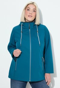 Veste imperméable turquoise avec capuche, fermeture éclair à l'avant et cordons de serrage réglables. Dotée de deux poches latérales zippées et de manches légèrement évasées.