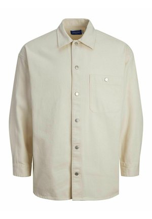 Cream-colored long-sleeve button-up shirt made of fabric with a smooth texture. Features a single pocket and silver snap buttons.