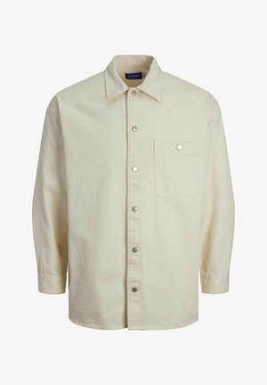 Kremna košulja dugih rukava s dugim gumbima izrađena od tkanine s glatkom teksturom. Ima jedan džep i srebrne gumbe sa kopčama.