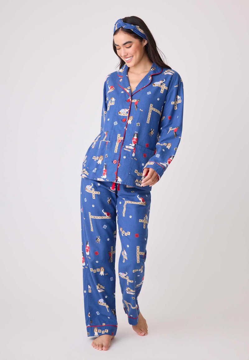Blaues Schlafanzug-Set mit einem verspielten Muster und lustigen Motiven, roten Akzenten und einem Stehkragen. Weicher Stoff und lockere Passform.