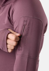 Maglietta sportiva a maniche lunghe in tessuto malva, con una tasca con zip sul braccio sinistro e cuciture piatte per un comfort e una vestibilità migliorati.