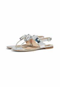 Sandali metallici argento con suola piatta, design aperto sulla punta e cinturino regolabile alla caviglia. Presentano dettagli decorativi in metallo.