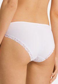 Weiße Baumwollunterhose mit Spitzenbesatz entlang der Beinöffnungen, weich im Griff und mit mittelhohem Schnitt. Die Rückansicht betont das Spitzen-Detail.