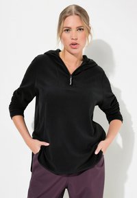 Felpa nera con zip, dotata di tasca frontale, maniche lunghe e una vestibilità rilassata. Realizzata in un tessuto morbido con una texture liscia. Accentuata da una piccola cerniera.