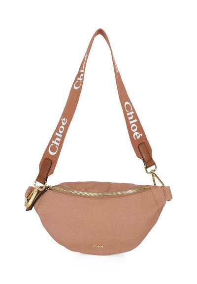 Sac bandoulière en toile rose avec une fermeture éclair dorée, des accents en cuir marron et une bandoulière réglable à logo imprimé. Texture lisse, forme ovale.