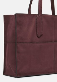 Bordowa torba na ramię z weluru z dwoma krótkimi uchwytami, o prostokątnym kształcie, czystych liniach i kontrastującym przeszyciu. Posiada zewnętrzne kieszenie do przechowywania.