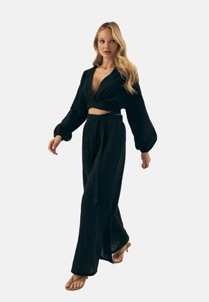 Schwarzes, leichtes zweiteiliges Outfit bestehend aus einem Wickel-Crop-Top mit langen Ärmeln und hoch taillierten, weit geschnittenen Hosen mit einem Bindegürtel.