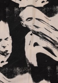 Black and cream textile featuring abstract, monochromatic human faces with blurred edges and contrasting textures.