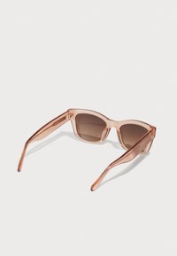 Transparent peach-colored sunglasses with a geometric cat-eye shape, tinted brown lenses, and slim, smooth arms.