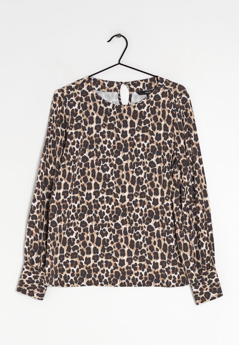 Blouse à manches longues avec motif léopard suspendue à un cintre noir sur fond blanc.