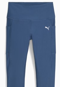 Leggings bleu marine avec une large ceinture, des poches latérales et un logo Puma blanc en contraste. Fabriqués en tissu extensible avec une texture lisse.