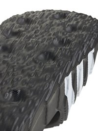 Crna potplata cipele s teksturiranim, valovitim uzorkom i uzdignutim područjima; ima bijele naglaske i složen dizajn duž rubova.