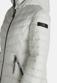 Podpinka w jasnoszarym kolorze, z kieszenią na zamek, szarym sznurkiem ściągającym i czarną łatką z logo na ramieniu. Pikowana tekstura.