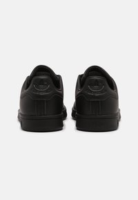 Svarta läder sneakers med en slät yta, med en upphöjd logotyp på hälen, låg design och gummiyttersula.