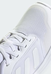 Chaussure de sport blanche avec une tige en mesh texturé, des accents synthétiques lisses et des lacets ronds. Comprend une semelle rembourrée pour le soutien.