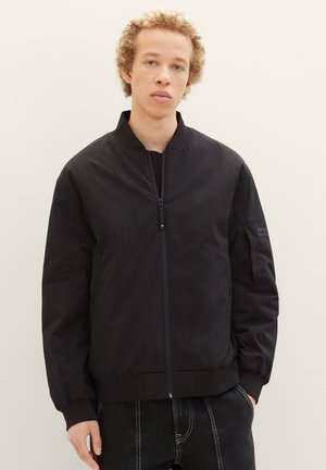 Black bomber jacket with a zip front, ribbed collar and cuffs, side pockets, and minimal detailing for a sleek, modern look.
