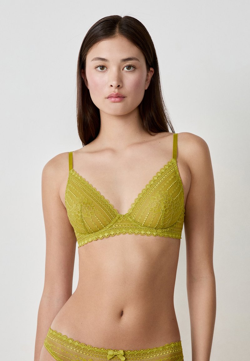 Kanten bralette in olijfgroen, met een driehoekige vorm, gegolfde randen en dunne verstelbare banden. Gedetailleerd bloemenpatroon over het geheel.