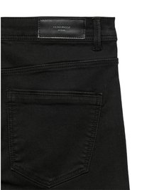 Fekete farmernadrág texturált felülettel, bőr derékpánt címkével, varrott díszítésekkel és egy hátsó zsebbel.