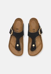 Sandali neri in pelle con suola in sughero, caratterizzati da un design elegante, cinturino regolabile con fibbia dorata e un bottone decorativo.