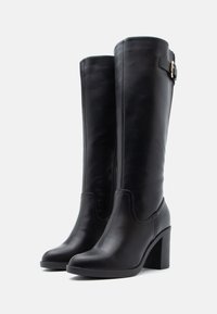 Black knee-high boots made of smooth leather, featuring a rounded toe, high block heel, and a side buckle detail.