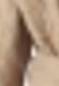 Tela beige con una textura suave, que presenta un acento en marrón oscuro. El diseño tiene una forma sencilla y limpia con hardware mínimo.