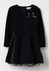 Navy velvet dress with a fitted bodice and flared skirt; features a decorative black bow with multicolored gems on the front. Long sleeves.