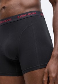 Fekete pamut boxer alsónadrág sima textúrával, piros "BJÖRN BORG" logóval a derekán és varrott részletezéssel.