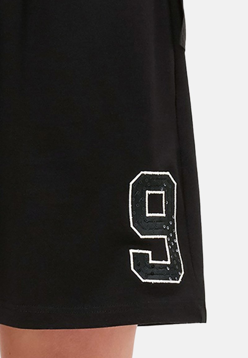 Zwarte shorts met een groot omrande cijfer 9 gedrukt bij de zoom aan het linkerbeen.