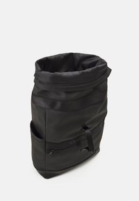 Zaino nero a roll-top realizzato in tessuto resistente con una texture liscia, dotato di una tasca anteriore con zip e spallacci regolabili.