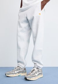 Light gray sweatpants made of soft material, featuring an elastic waistband and side pockets, paired with gray and blue athletic shoes.
