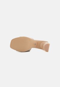Beige høyhælte sandaler med en jevn finish, rund tå og solid blokkhæl. Sålen er teksturert for godt grep.