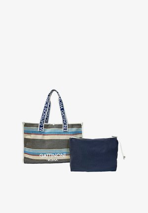 Sac cabas rayé avec des bandes bleues, blanches et rouges, poignées bleues avec texte blanc, et une pochette zippée unie bleu marine séparée.