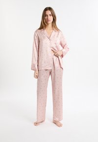 Różowe piżamy w paski z kwiatowymi wzorami, długimi rękawami oraz zapięciem na guziki z przodu. Spodnie są luźne, z elastycznym pasem.