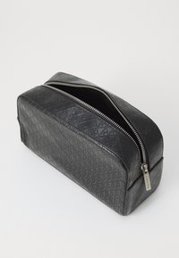 Black textured cosmetic bag with a geometric pattern, featuring a silver zipper and branded pull tab, rectangular design, and smooth finish.