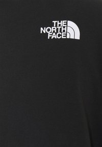 T-shirt noir avec col rond, fabriqué en coton lisse. Présente un texte logo blanc et un design en arc "THE NORTH FACE" sur la poitrine gauche.