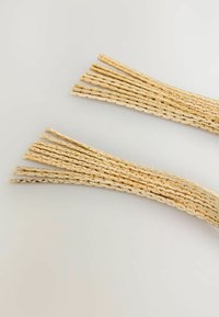 Zeltaini, teksturēti pavedieni ar pinumu rakstu, sakārtoti izkaisītā izkārtojumā. Katrs pavediens ir spīdīgs un plakans.