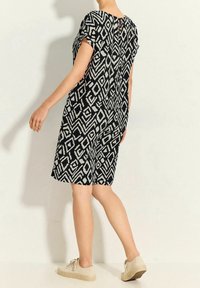 Kortärmad klänning i knälängd med ett svart och vitt geometriskt mönster. Mjuk tyg med en något lös passform och öppning i nacken bak.