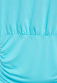 Tessuto azzurro chiaro con pieghe orizzontali che creano una texture arricciata al centro e sul lato sinistro.