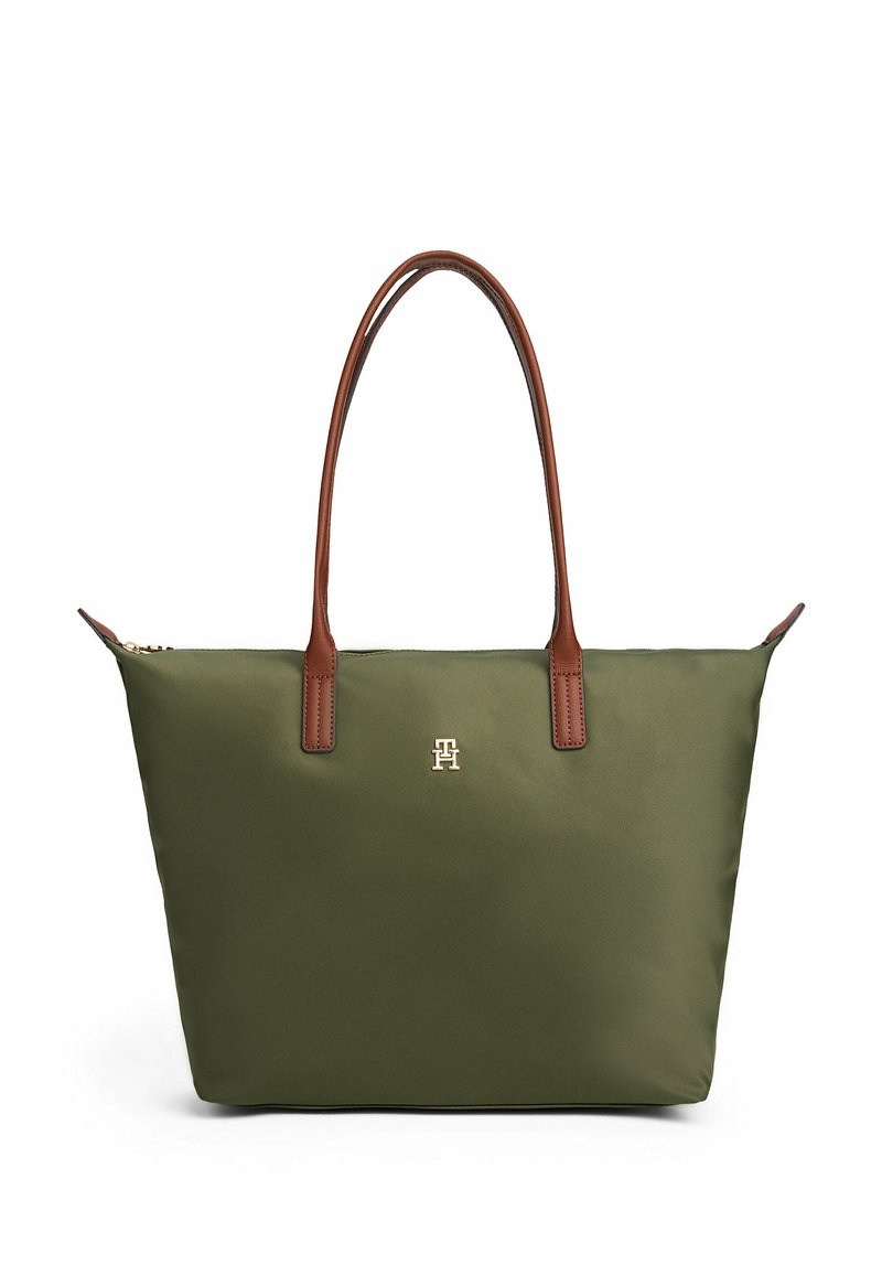 Groene tote bag met bruine leren handvatten en een klein gouden embleem aan de voorkant, weergegeven op een witte achtergrond.