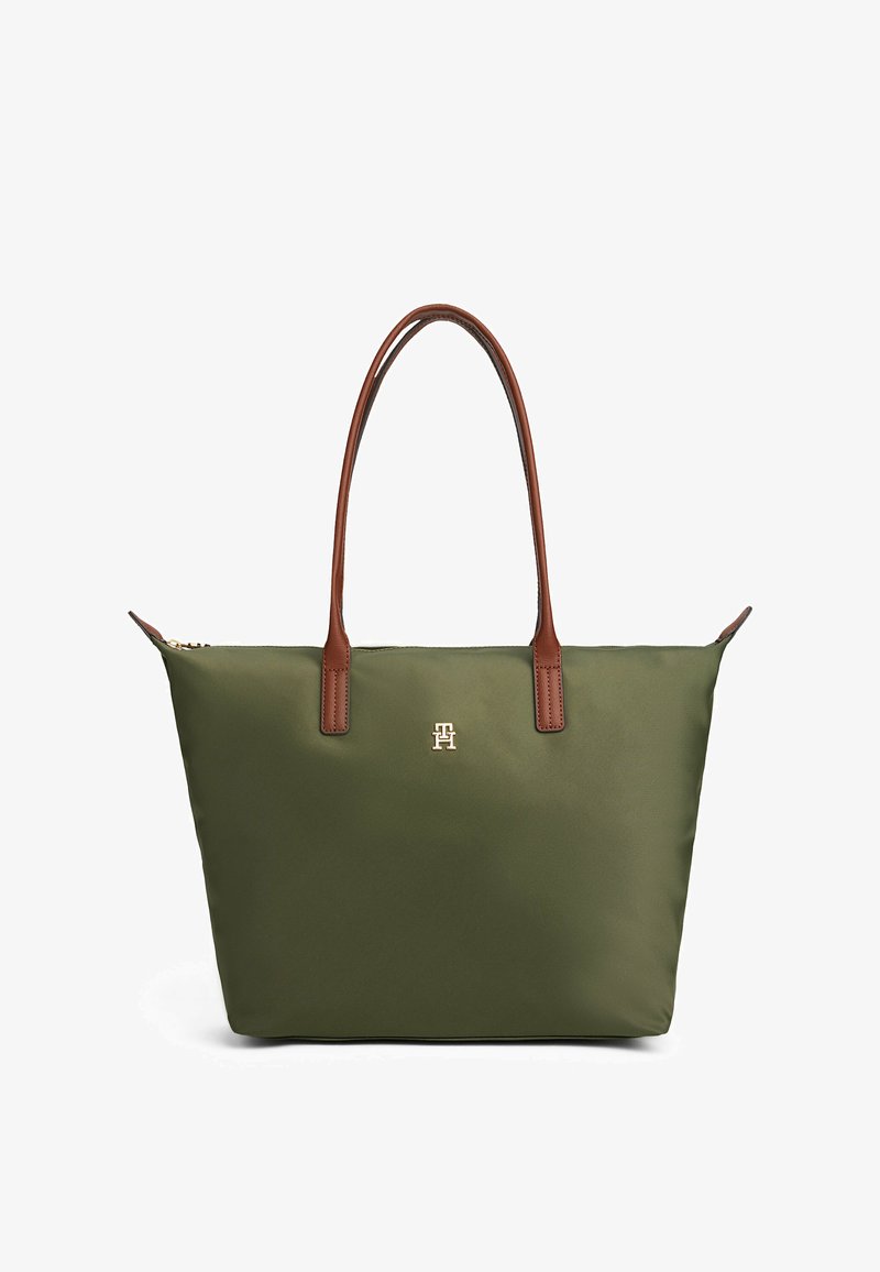 Groene tote bag met bruine leren handvatten en een klein gouden embleem aan de voorkant, weergegeven op een witte achtergrond.