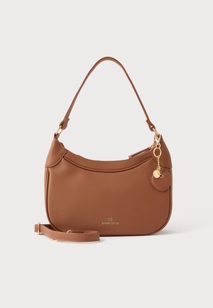 Sac à main en cuir marron texturé avec une seule bandoulière, une lanière bandoulière amovible et un charm en forme de cœur doré sur fond blanc.