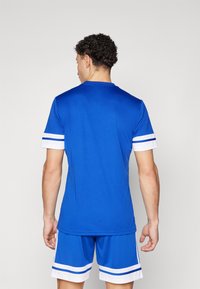 Blue athletic jersey with white stripes on sleeves, made from lightweight fabric. Paired with matching blue shorts featuring white accents.